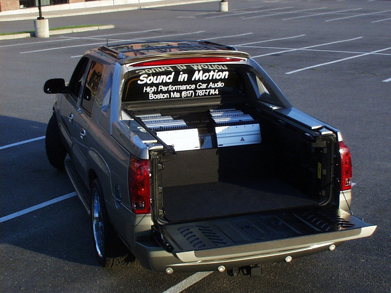 The Cadillac EXT has factory watertight covers that cover the bed, but once removed you can see the (8) JL Audio amplifiers arranged on the top of the sub enclosures on either side. Notice that half of the bed still has been retained for storage. A custom snap-in floor mat was made for the cargo area.