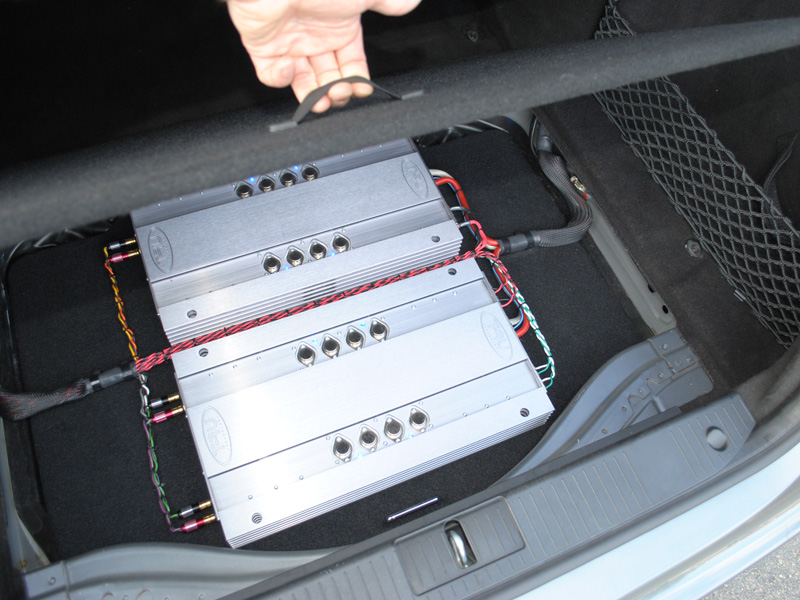 If you lift up the spare tire cover you will find two TRU Technology "custom built to order" Amplifiers. The spare tire is still accessible by lifting the amp rack up.